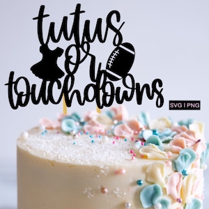 Puede incluir: Un pastel blanco decorado con flores de crema de mantequilla rosa pastel y azul y chispas plateadas. Un adorno de pastel negro dice "Tutus or Touchdowns" con una silueta de una bailarina y una pelota de fútbol.