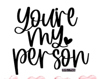 May include: Black and white calligraphy text that reads "you're my person" with a small heart symbol above the word "my". Four pink heart-shaped macarons are arranged in a row below the text.