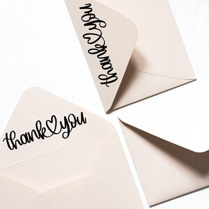 May include: Three light brown envelopes with black calligraphy. One envelope says "thank you" with a heart symbol. Another envelope says "from you".