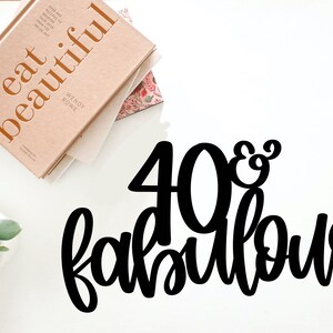 May include: Black and white 40 & Fabulous cake topper. The number 40 is large and the word fabulous is in a script font.