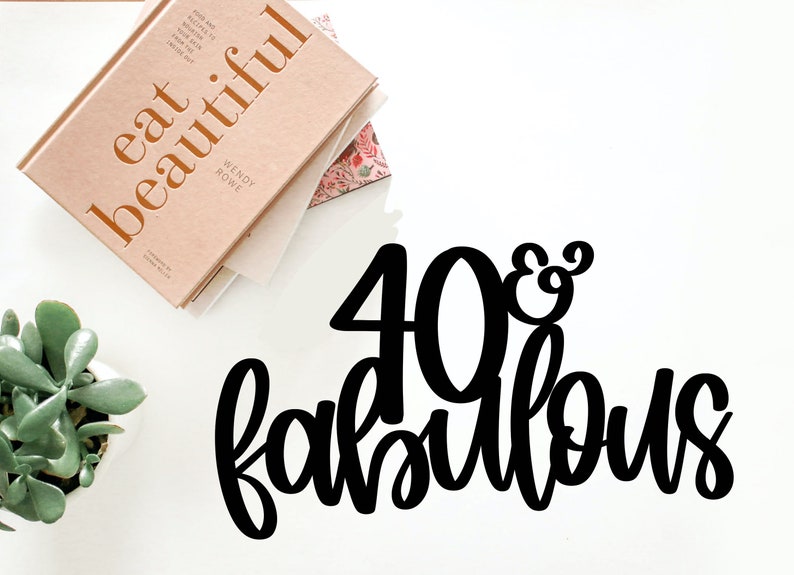 May include: Black and white 40 & Fabulous cake topper. The number 40 is large and the word fabulous is in a script font.