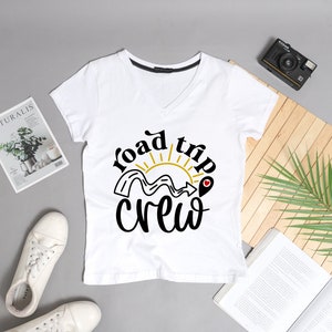 May include: White t-shirt with a black and gold graphic that says "Road trip crew" with a sun and a road design.