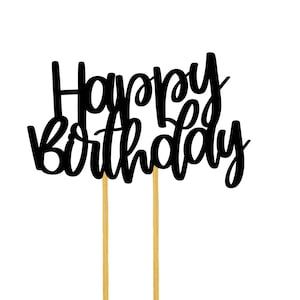 Puede incluir: Topper de pastel negro con el texto "Happy Birthday" en una fuente cursiva. El topper est&aacute; unido a dos palillos de dientes dorados.