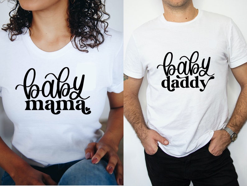 May include: Two white t-shirts with black text. One shirt says "baby mama" and the other says "baby daddy".