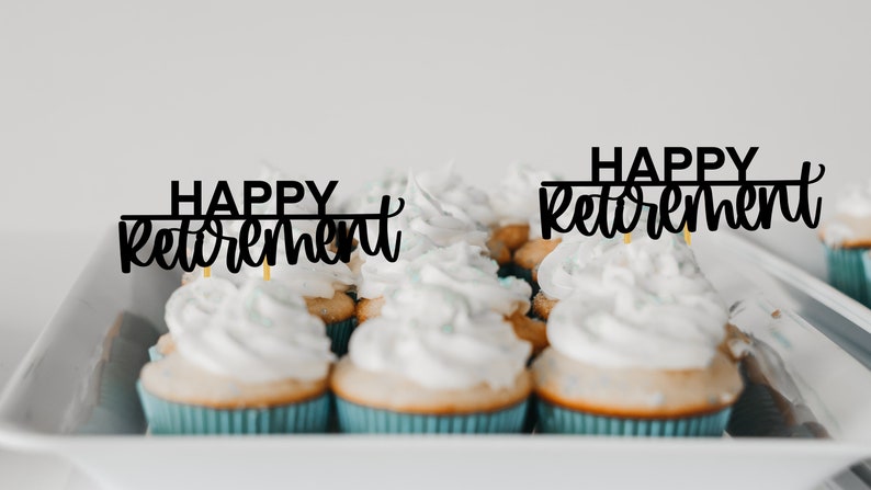 May include: A tray of cupcakes with white icing and blue cases. Two of the cupcakes have black toppers that say "Happy Retirement".