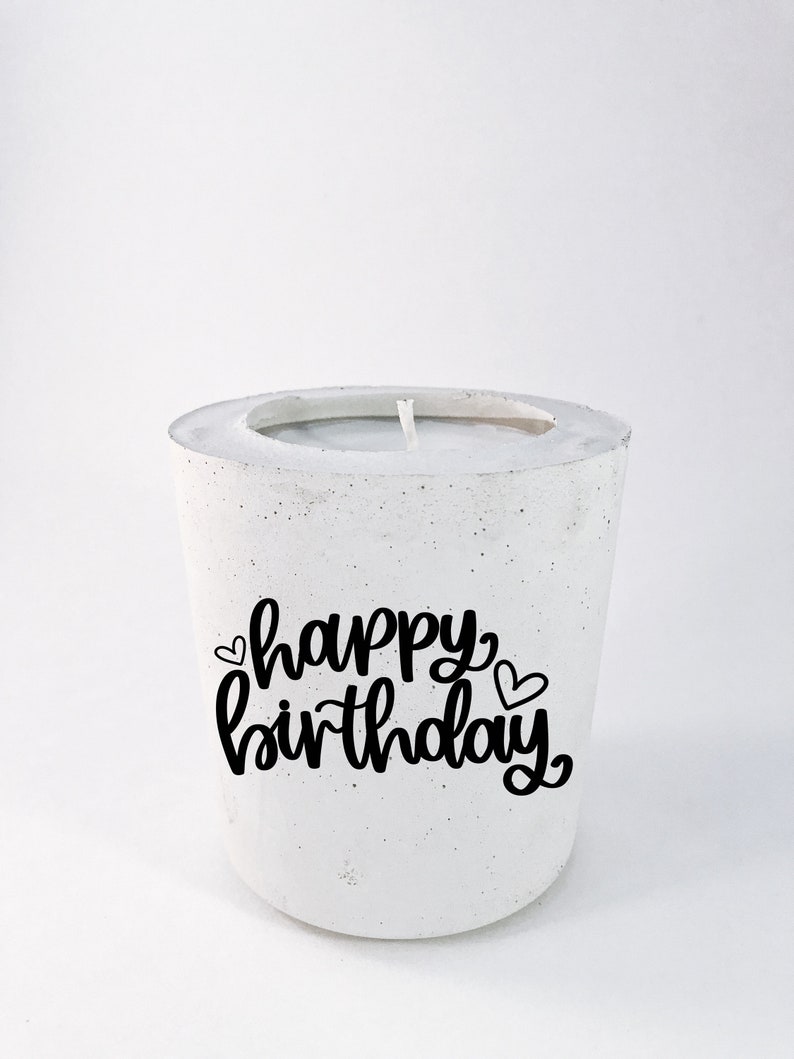 May include: White concrete candle holder with a black inscription that reads "happy birthday" with two small hearts.