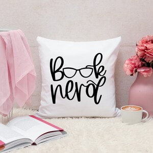 May include: White pillow with black text that reads "Book Nerd" and a pair of glasses graphic.