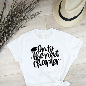 May include: White t-shirt with black text that reads "On to the next chapter" with a graduation cap graphic above the text.