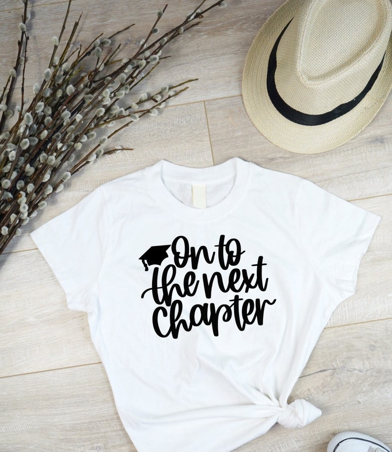 May include: White t-shirt with black text that reads "On to the next chapter" with a graduation cap graphic above the text.