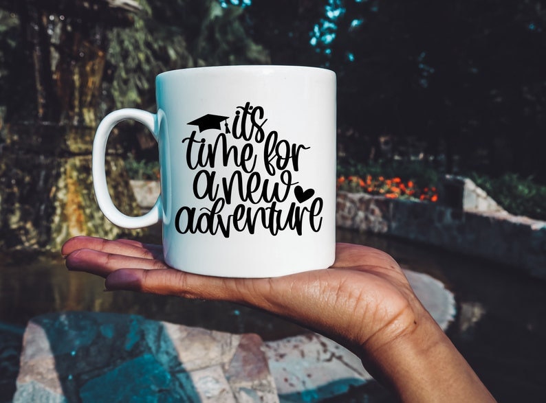 May include: White ceramic mug with a black graphic that reads "It's time for a new adventure" with a graduation cap and a heart.