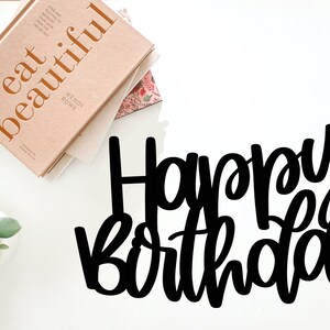 Puede incluir: Letras recortadas en negro que deletrean "Happy Birthday" sobre un fondo blanco.