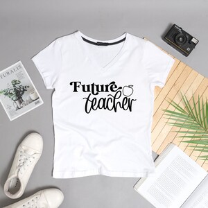 May include: White v-neck t-shirt with the text "Future Teacher" and a red apple graphic.