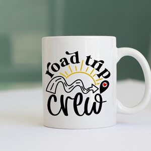 May include: White ceramic mug with a black and gold design that says "road trip crew". The design features a winding road, a sun, and a red heart.