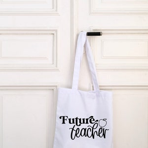 May include: White tote bag with black text that says "Future teacher" and a small apple graphic.