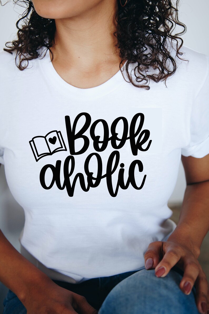 May include: White t-shirt with black text that reads "Bookaholic" and a small black illustration of an open book with a heart on the page.