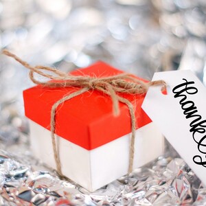 May include: A small red and white gift box tied with twine and a white gift tag that says "Thank You".