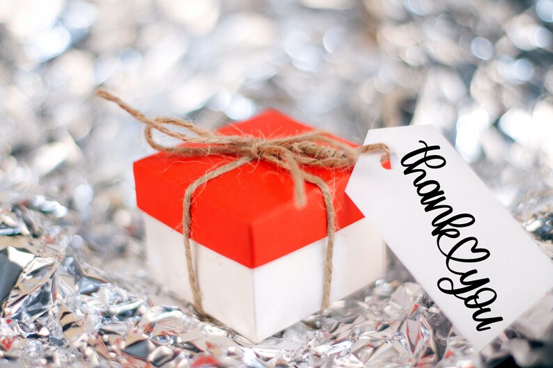 May include: A small red and white gift box tied with twine and a white gift tag that says "Thank You".