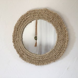Può includere: Uno specchio rotondo con una cornice in corda di juta naturale. La cornice è spessa e ha una trama intrecciata.