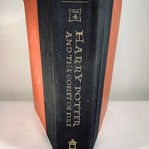 May include: A black hardcover book with a red spine. The book is titled "Harry Potter and the Goblet of Fire" and is part of the "Year 4" series. The book is published by Arthur A. Levine Books, Scholastic.