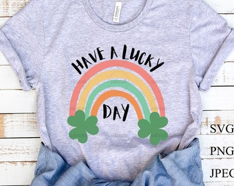 May include: A gray t-shirt with a rainbow design and the text "Have a Lucky Day" in black. Two green shamrocks are on either side of the rainbow.