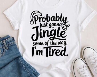 May include: White t-shirt with the text "Probably just gonna Jingle some of the way. I'm Tired." The text is in black, with a Santa hat and bell graphic. The shirt is paired with blue jeans and white sneakers.
