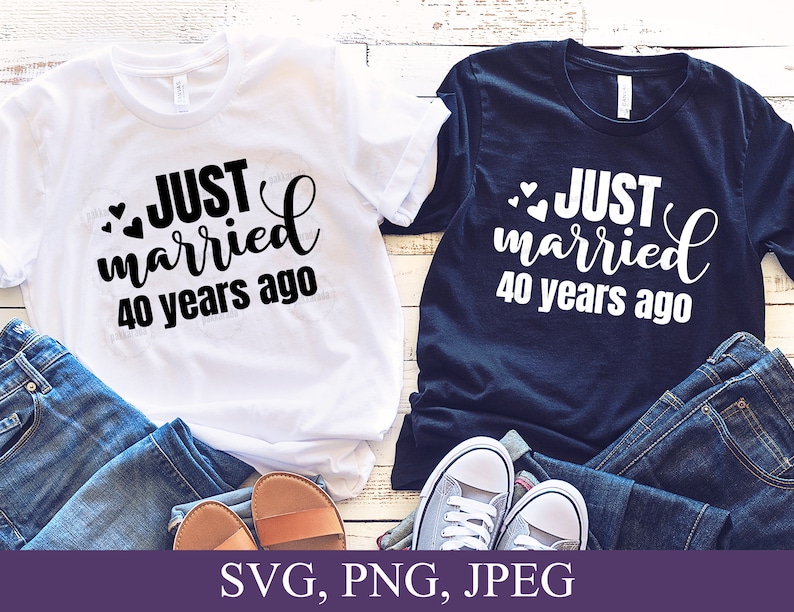 May include: Two white t-shirts with black text that reads "JUST married 40 years ago" and two black t-shirts with white text that reads "JUST married 40 years ago". The shirts are laid out on a wooden surface with blue jeans and sandals.