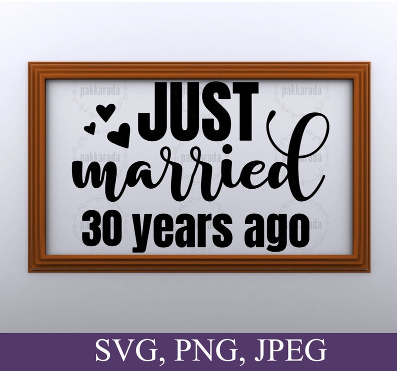 May include: A brown wooden frame with a white background and black text that reads "JUST married 30 years ago". There are three small hearts above the word "JUST".