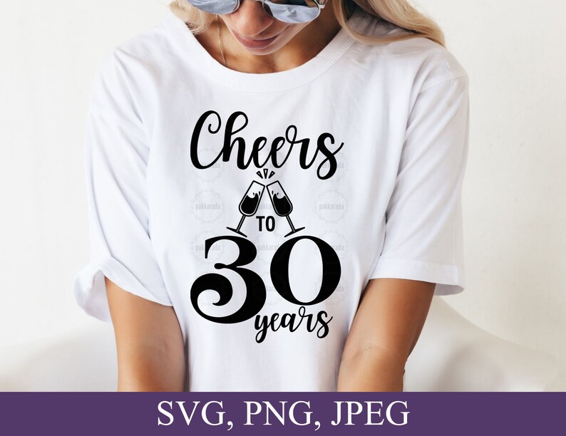 May include: White t-shirt with the text "Cheers to 30 years" in black script. The design includes two champagne glasses clinking together. The bottom of the image shows the text "SVG, PNG, JPEG" in white on a purple background.