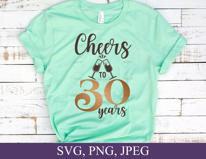 May include: A mint green t-shirt with the words "Cheers to 30 years" in brown and gold lettering. The design includes two champagne glasses clinking together. The bottom of the shirt has the file types: SVG, PNG, JPEG.