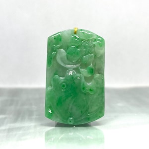 May include: A green jade pendant featuring intricate carvings of flowers and leaves. The pendant is rectangular in shape and has a hole at the top for a string or chain.