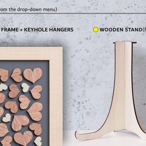 May include: Two options for displaying a wooden heart guest book: a wooden frame with keyhole hangers and a wooden stand. The frame is light brown and the stand is natural wood.