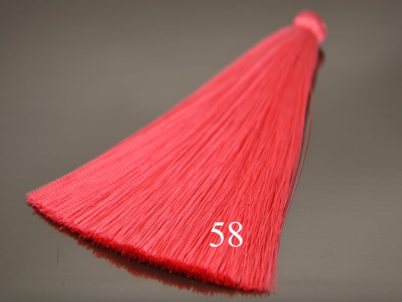 May include: A bright red tassel with a number 58 printed on it. The tassel is made of thin, silky threads and is approximately 10 inches long.