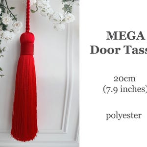 May include: A bright red polyester door tassel featuring a braided hanging cord and a dense, long fringe. The text MEGA Door Tassel, 20cm (7.9 inches), and polyester is printed on the right side of the image.