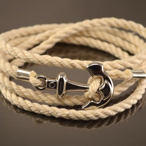 Puede incluir: Un brazalete de cuerda blanca con un dije de ancla de plata. El brazalete está hecho de cuerda de algodón natural y es ajustable para adaptarse a la mayoría de las muñecas.