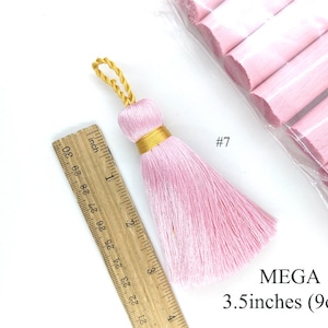 May include: A pink tassel with a gold cord and a 3.5 inch (9 cm) length. The tassel is shown next to a ruler for size reference. #7 MEGA