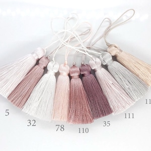 May include: Seven different colours of tassel trim, including light pink, white, blush, mauve, and grey. The tassels are numbered 4, 5, 32, 78, 110, 111, 112, 113, and 35.