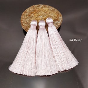 May include: Three light pink silk tassels with a beige background. #4 Beige