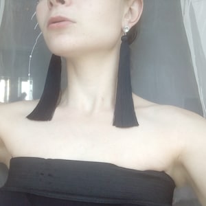 Könnte beinhalten: Ein Paar lange schwarze Quastenohrringe mit einer kleinen silbernen Perle oben.
