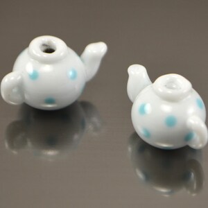 Puede incluir: Dos cuentas de cer&aacute;mica blanca en forma de tetera con lunares azules. Las cuentas son peque&ntilde;as y ser&iacute;an perfectas para hacer joyas.