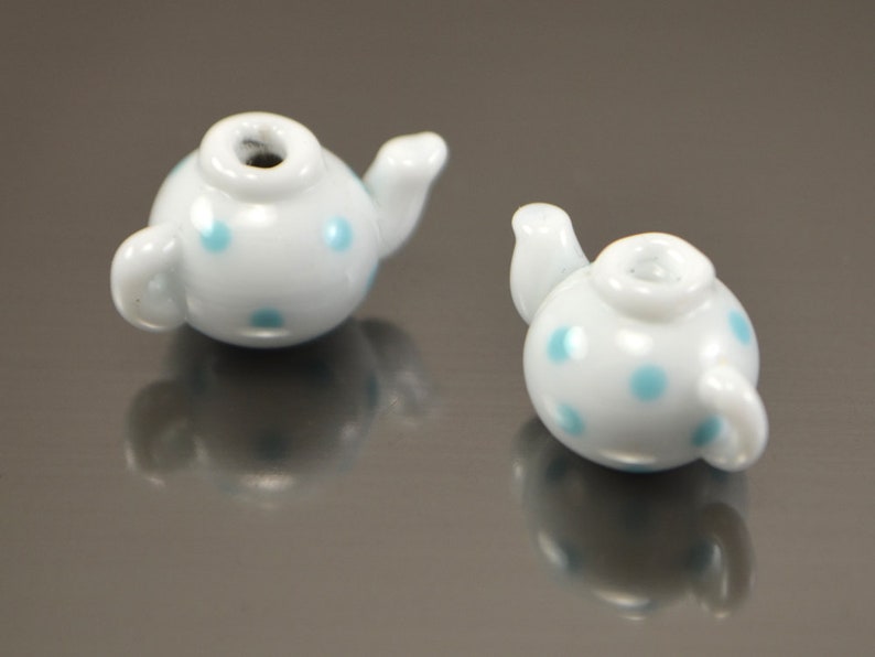 Puede incluir: Dos cuentas de cer&aacute;mica blanca en forma de tetera con lunares azules. Las cuentas son peque&ntilde;as y ser&iacute;an perfectas para hacer joyas.