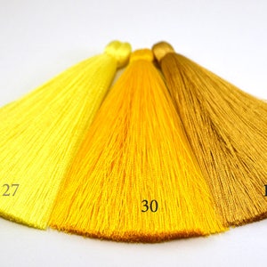 May include: Three yellow and gold silk tassels, with the numbers 27, 30, and 15 printed on them.