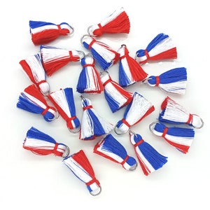 May include: A group of red, white, and blue tassel charms with silver rings. The tassels are made of yarn and are approximately 1 inch in length.