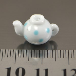 Puede incluir: Una tetera blanca peque&ntilde;a con lunares azules. La tetera mide aproximadamente 2,5 cm de alto y est&aacute; hecha de cer&aacute;mica.