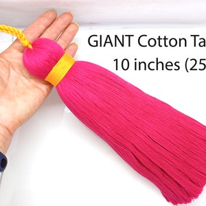 May include: A giant hot pink cotton tassel, 10 inches (25cm) long, with a yellow cord and band. The text "GIANT Cotton Tassel" is visible in the image.