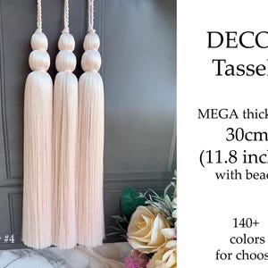 May include: Three blush-colored decorative tassels with beaded tops and long, thick strands. The text on the image reads "DECOR Tassels," "MEGA thickness 30cm (11.8 inches) with beads," and "140+ colors for choose."