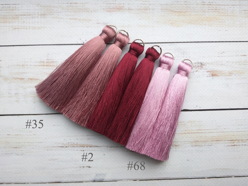 May include: Five silk tassels in shades of pink and burgundy. The tassels are labeled #35, #2, and #68.