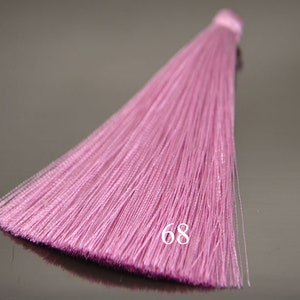 May include: A pink tassel with a long, flowing fringe. The tassel is made of soft, silky fibers and has a delicate, feminine look. The number 68 is printed on the tassel.