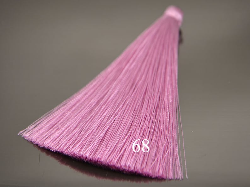 May include: A pink tassel with a long, flowing fringe. The tassel is made of soft, silky fibers and has a delicate, feminine look. The number 68 is printed on the tassel.
