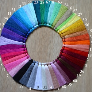 May include: A color chart of 68 different shades of embroidery floss, arranged in a circle. The floss is tied into tassels and labeled with numbers from 0 to 68.