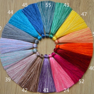 May include: A circle of colorful silk tassels with numbers from 24 to 55. The tassels are arranged in a circle on a wooden surface.